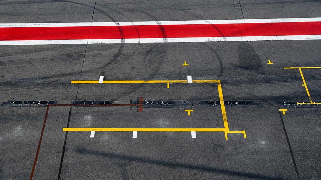 A pit lane seen along its length, with the speed limit line and empty boxes