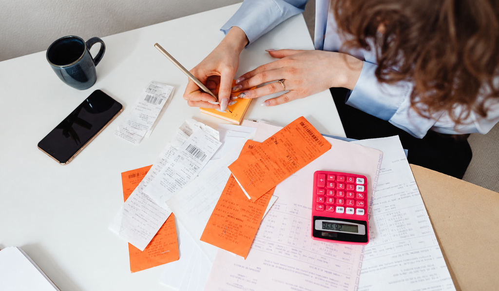 A calculator, receipts, and financial notes arranged on a desk for budget planning