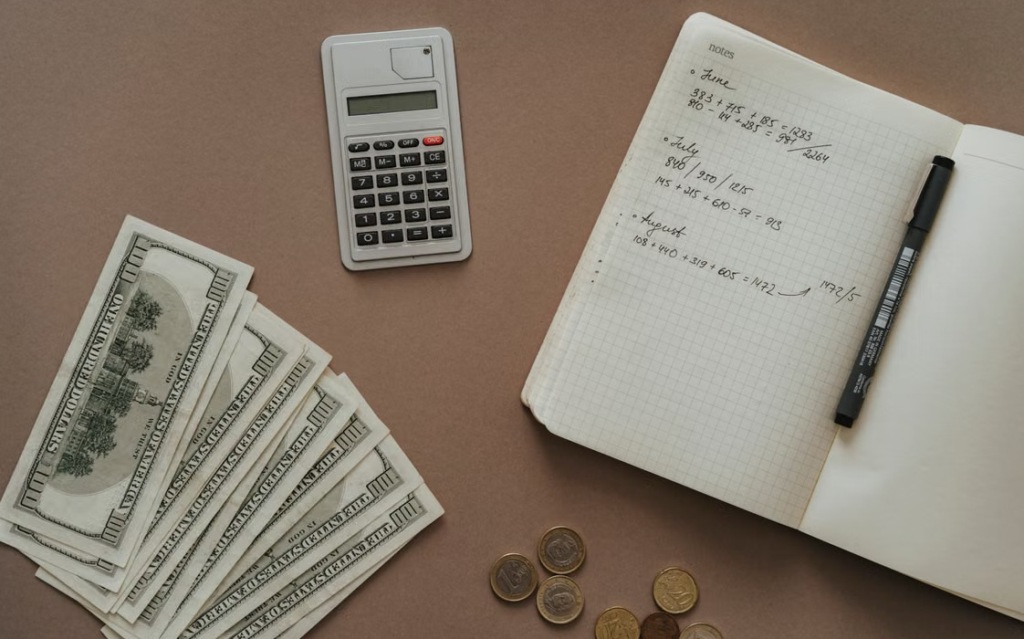 Calculator, notebook, and dollar bills arranged for financial planning