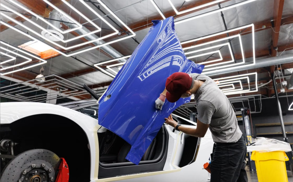 Vinyl film being applied to a car body in a professional automotive studio