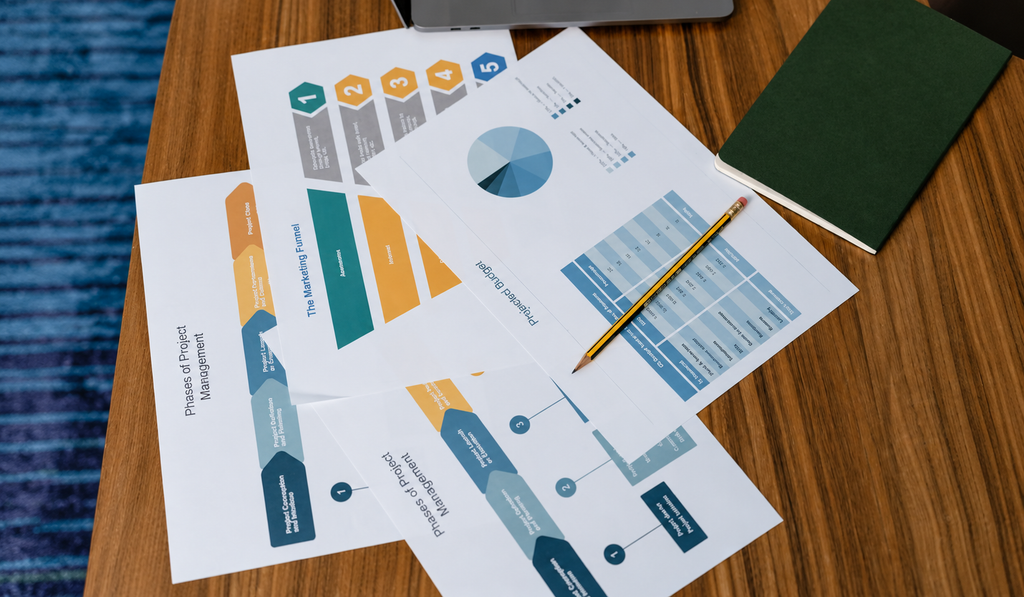 Printed documents and diagrams spread across a desk with a pencil
