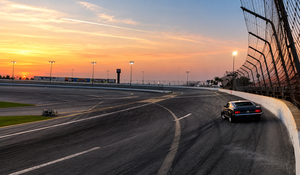 A race car speeding around a racetrack at sunset