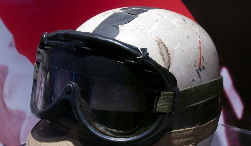 A weathered open-face racing helmet with a dark visor and strap on display.