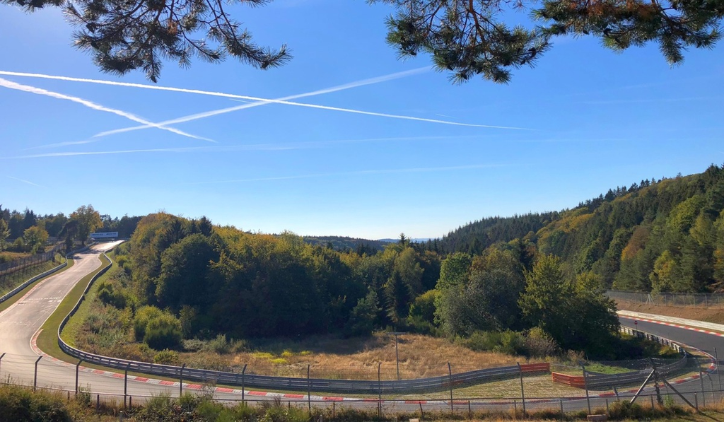 An empty, wooded bend on the Nürburgring Nordschleife, with guardrails following the track.
